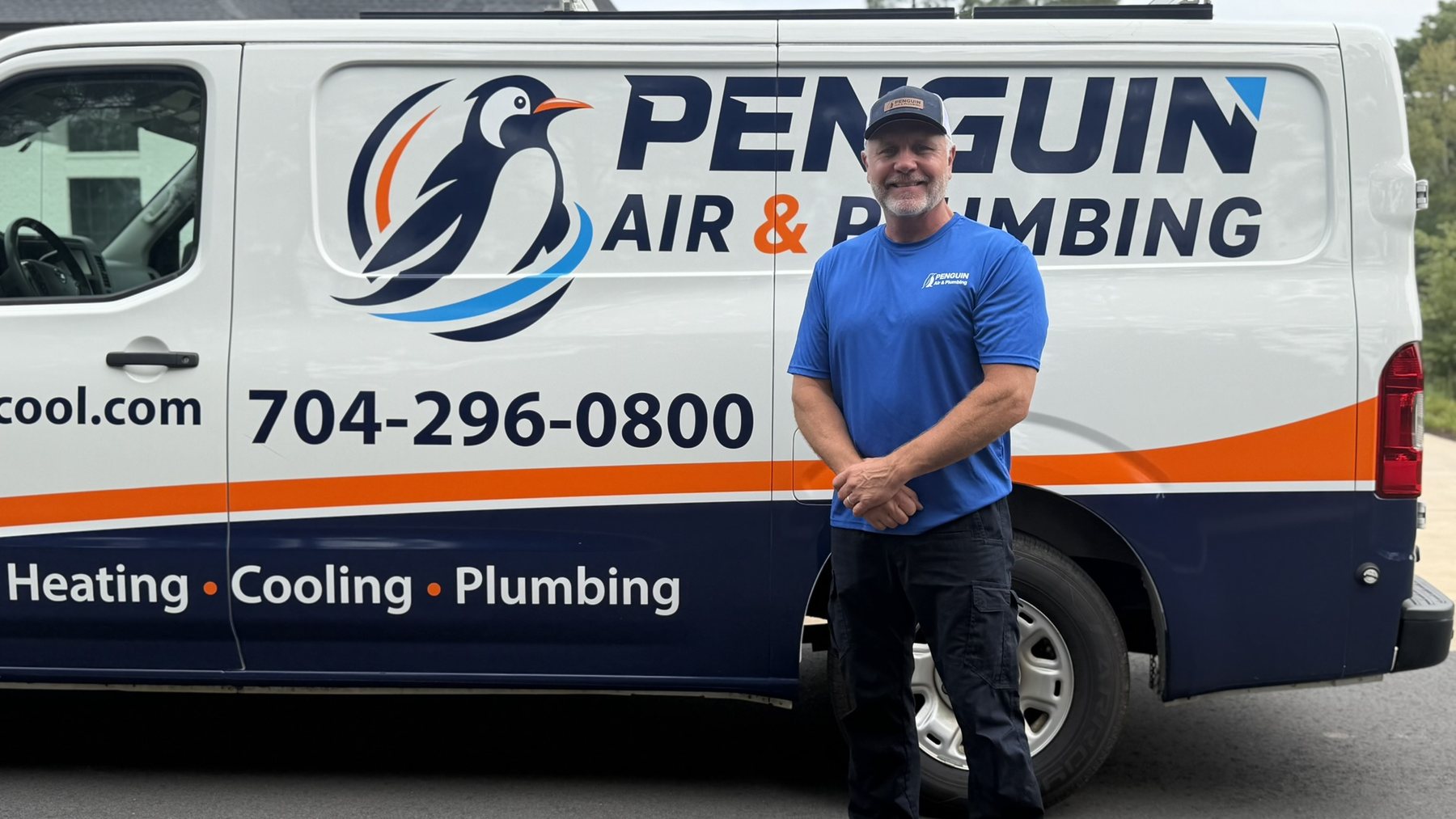 Randy Kemling, owner of Penguin Air & Plumbing, standing beside a Penguin service van
